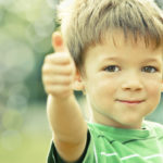 happy smiling kid outdoor doing OK portrait green tone